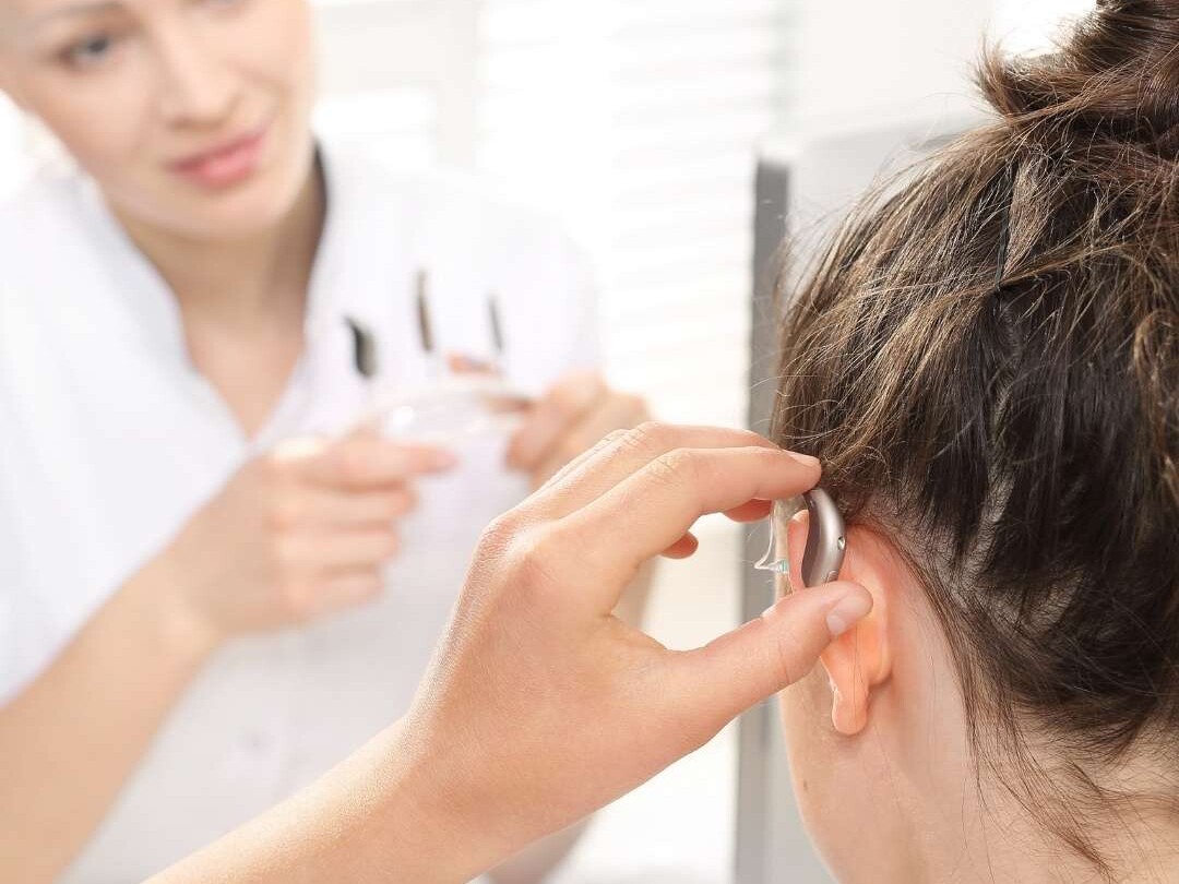 Hørespecialist hjælper kunde med at lære at isætte høreapparat
