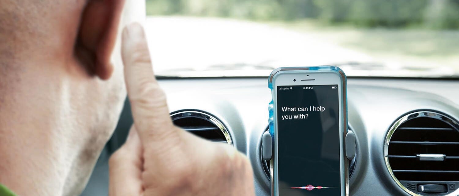 Mand med bluetooth h&oslash;reapparater og smartphone i bil