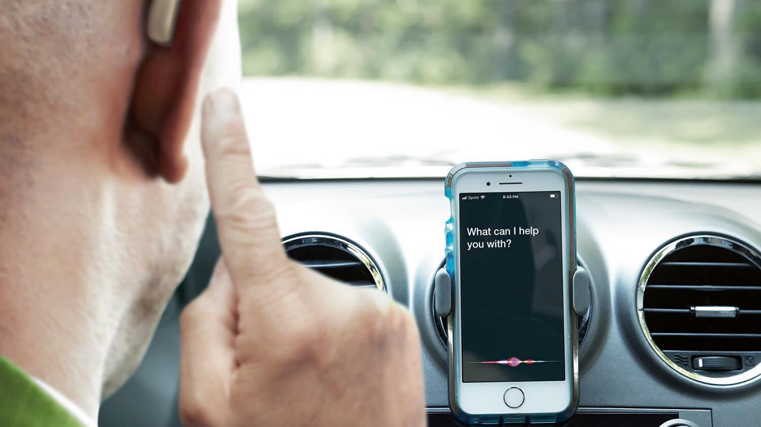 Mand med bluetooth høreapparater og smartphone i bil