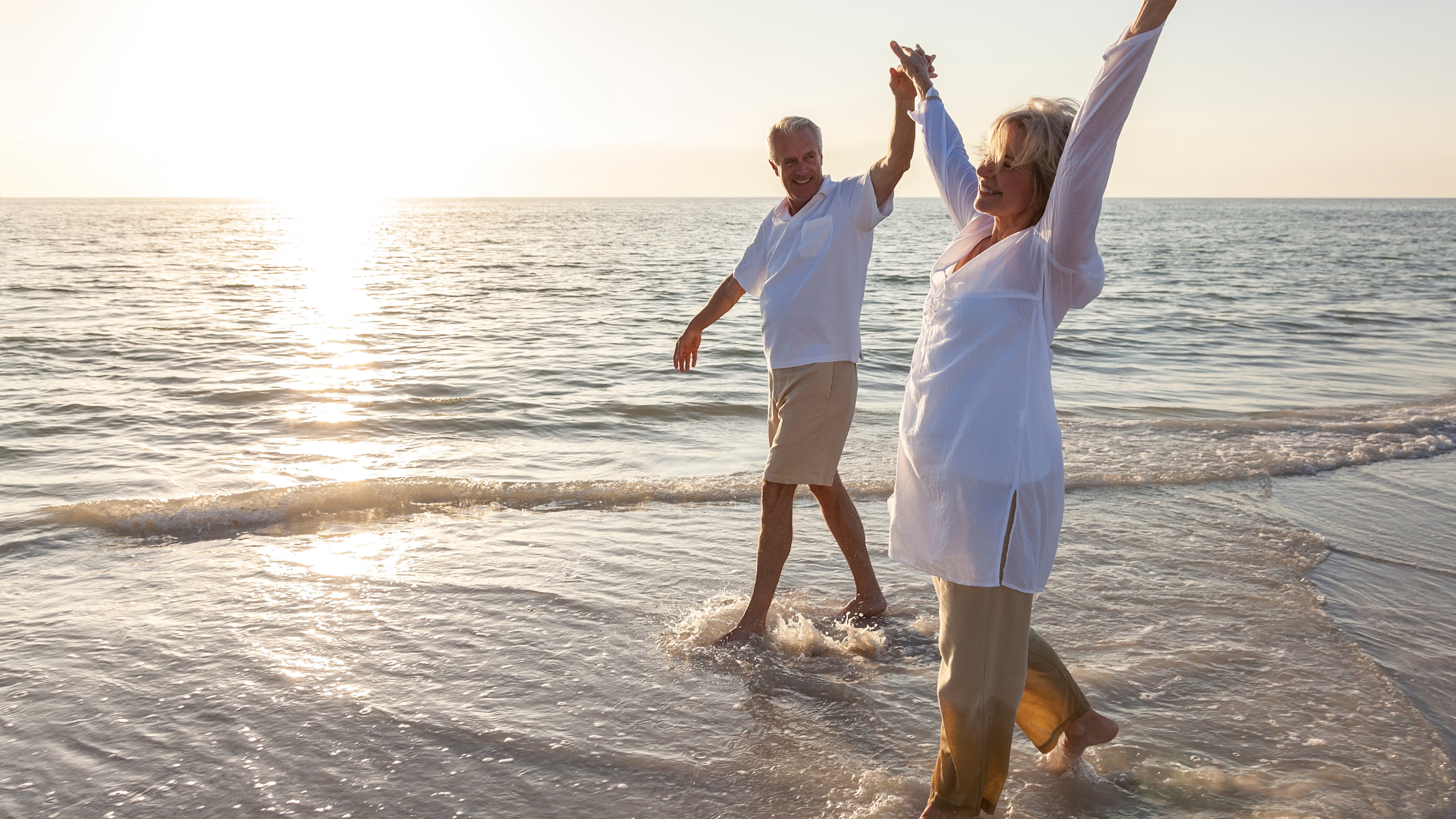 Two_elderly_people_cheering_holding_hands_on_the_beach